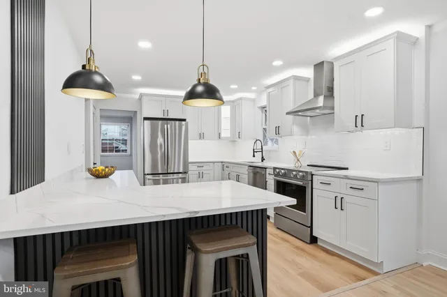 a kitchen with stainless steel appliances a stove a sink a kitchen island with chairs and wooden cabinets