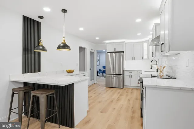 a kitchen with stainless steel appliances kitchen island granite countertop a table chairs sink and cabinets