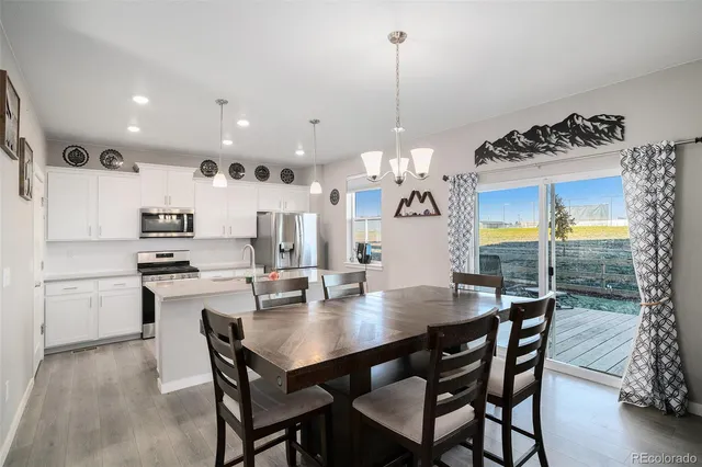 a kitchen with a dining table chairs and refrigerator