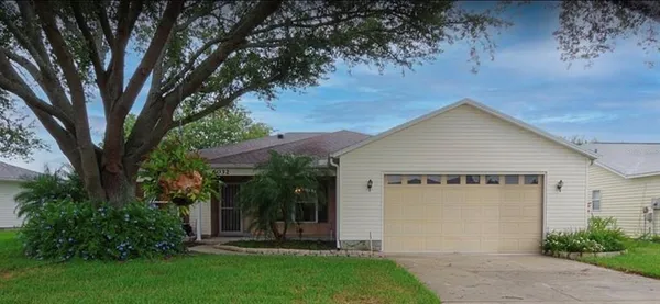 front view of house with a yard and trees all around