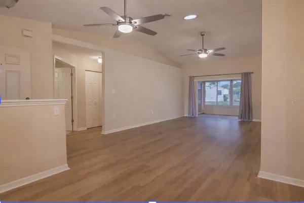 a view of an empty room with a window and wooden floor