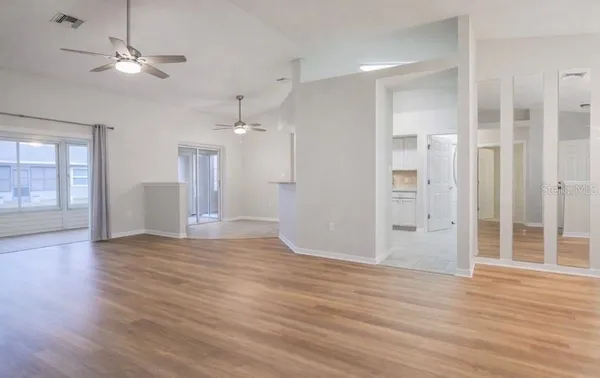 a view of an empty room with window and wooden floor