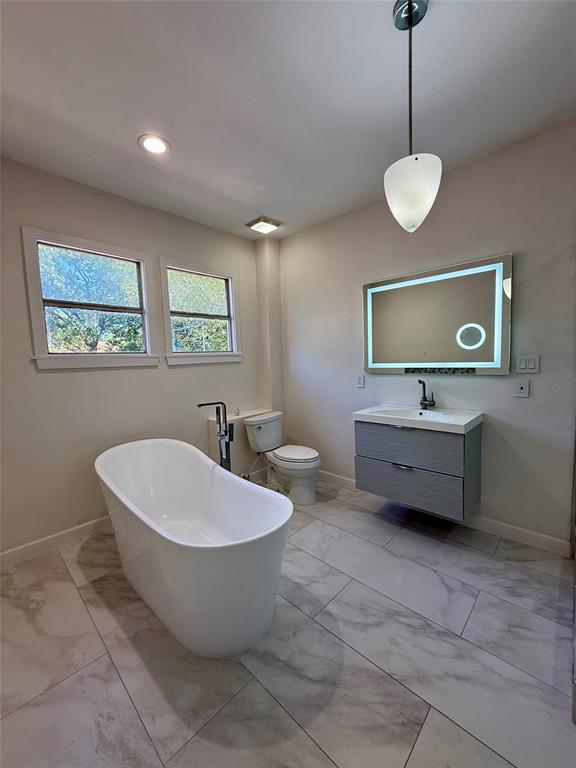 4810 Victor Street Dallas, TX 75246 - Photo 16 of 26 a spacious bathroom with a double vanity sink a mirror and a bathtub