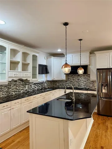 a kitchen with stainless steel appliances granite countertop a sink a stove and a wooden floors