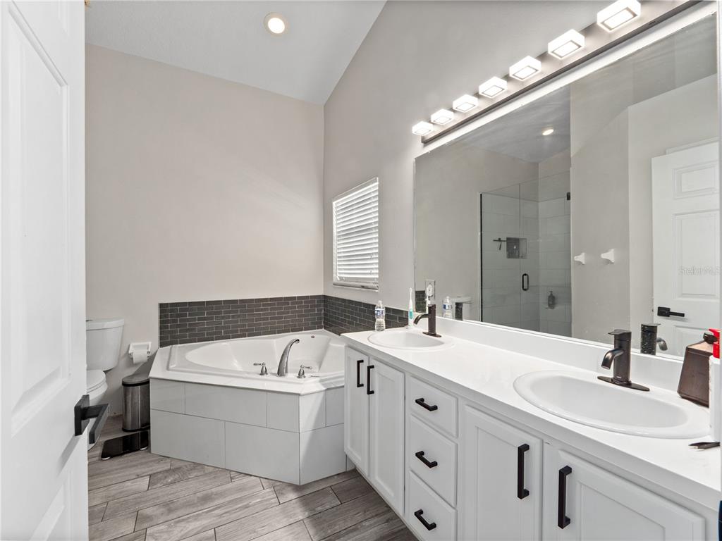 117 Rachel Lin Lane St. Cloud, FL 34771 - Photo 12 of 28 a bathroom with a double vanity sink a mirror and a bathtub