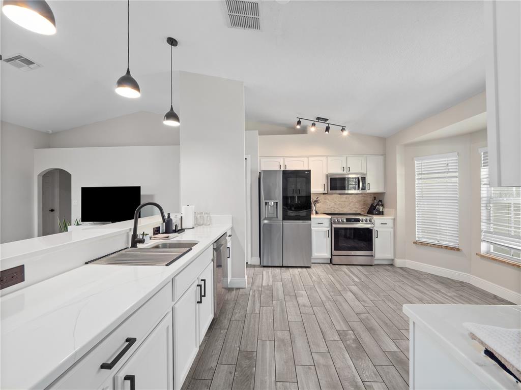 117 Rachel Lin Lane St. Cloud, FL 34771 - Photo 4 of 28 a large white kitchen with a stove a sink dishwasher a refrigerator and wooden floor