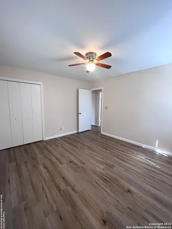 a view of empty room with wooden floor and fan