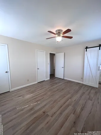 a view of an empty room with chandelier fan and wooden floor