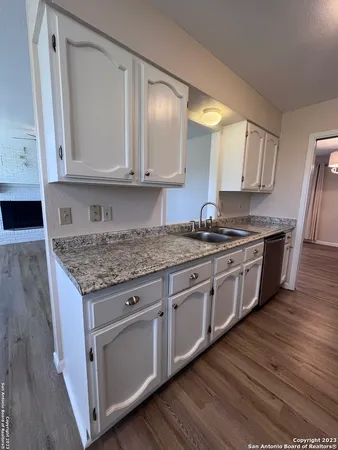 a kitchen with stainless steel appliances granite countertop a stove a sink and white cabinets with wooden floor