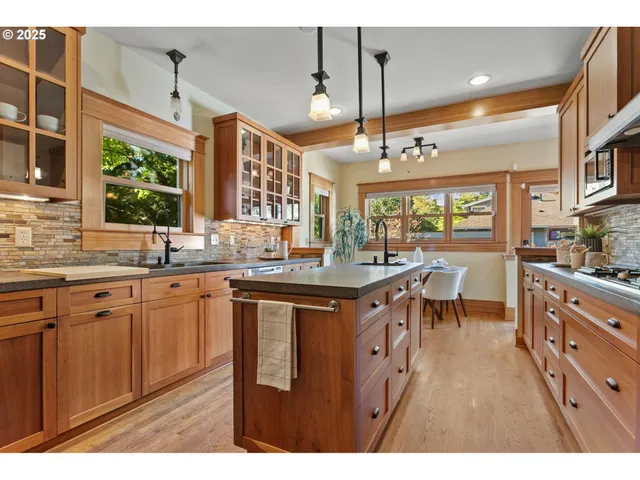 a open kitchen with stainless steel appliances granite countertop a stove a sink dishwasher and white cabinets with wooden floor