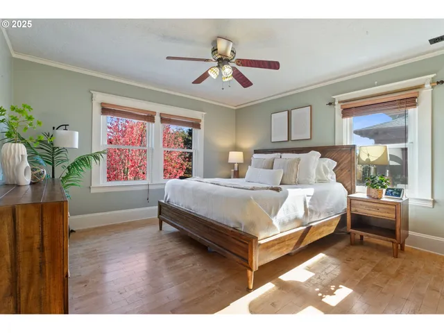 a bedroom with a bed painting on wall and a large window