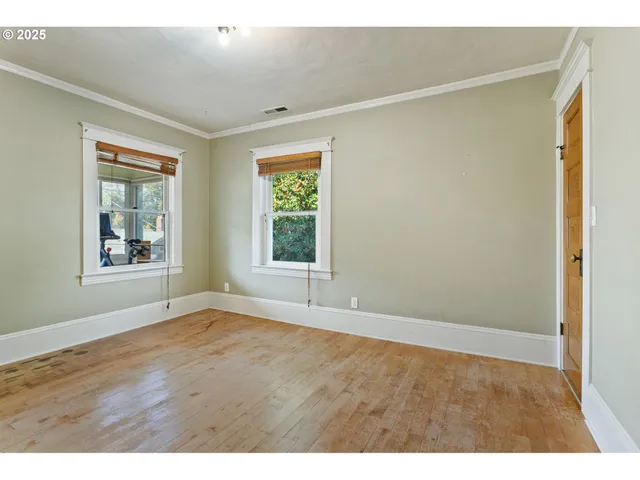a view of an empty room with window and wooden floor