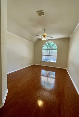 an empty room with wooden floor chandelier and windows