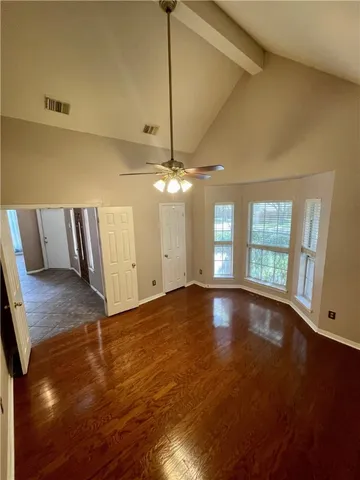 a view of an empty room with window and wooden floor