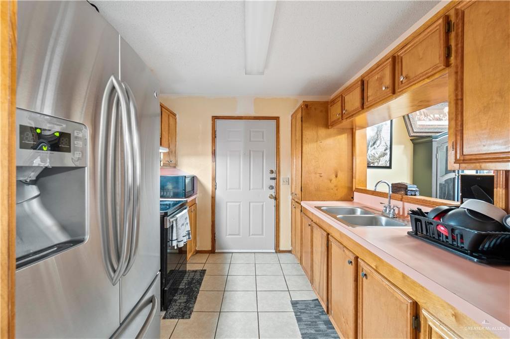 106 Rosa Priego Street Donna, TX 78537 - Photo 6 of 25 Kitchen with appliances with stainless steel finishes, sink, light tile patterned floors, and a textured ceiling