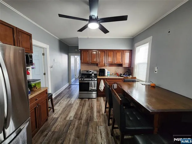 a kitchen with granite countertop a refrigerator a sink dishwasher a stove and white countertops with wooden floor