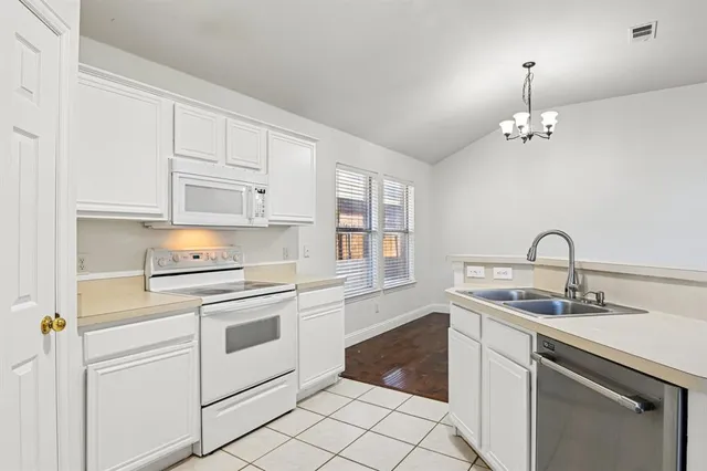 a kitchen with granite countertop white cabinets and white appliances