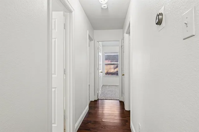 a view of a hallway with wooden floor and a kitchen