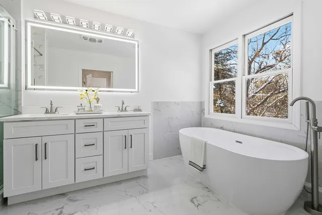 a spacious bathroom with a double vanity sink mirror and a bathtub