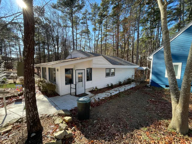 a view of a house with a yard chairs and wooden fence