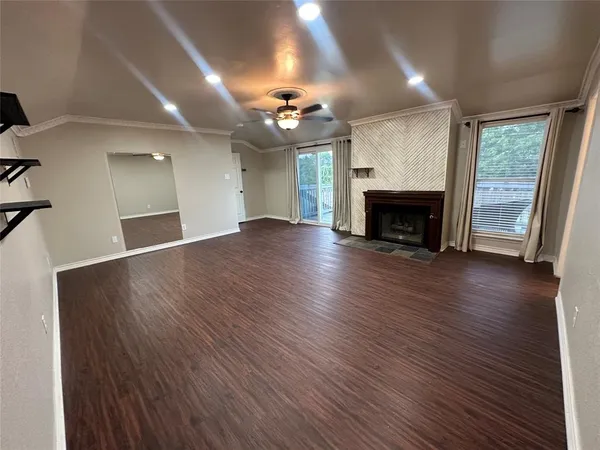 an empty room with wooden floor fireplace and windows