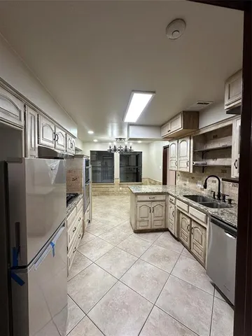 a kitchen with granite countertop a refrigerator and a stove top oven