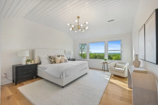a spacious bedroom with a large bed and a chandelier