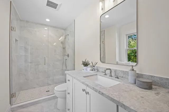 a bathroom with a granite countertop sink a toilet and shower