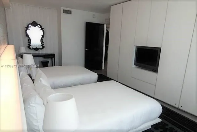 a bedroom with a bed and a flat tv screen on dresser