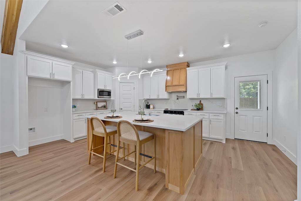 801 Tierney Road Fort Worth, TX 76112 - Photo 15 of 30 Kitchen featuring a central island with countertop, white cabinetry, wood-finish flooring, recessed lighting, and a modern chandelier