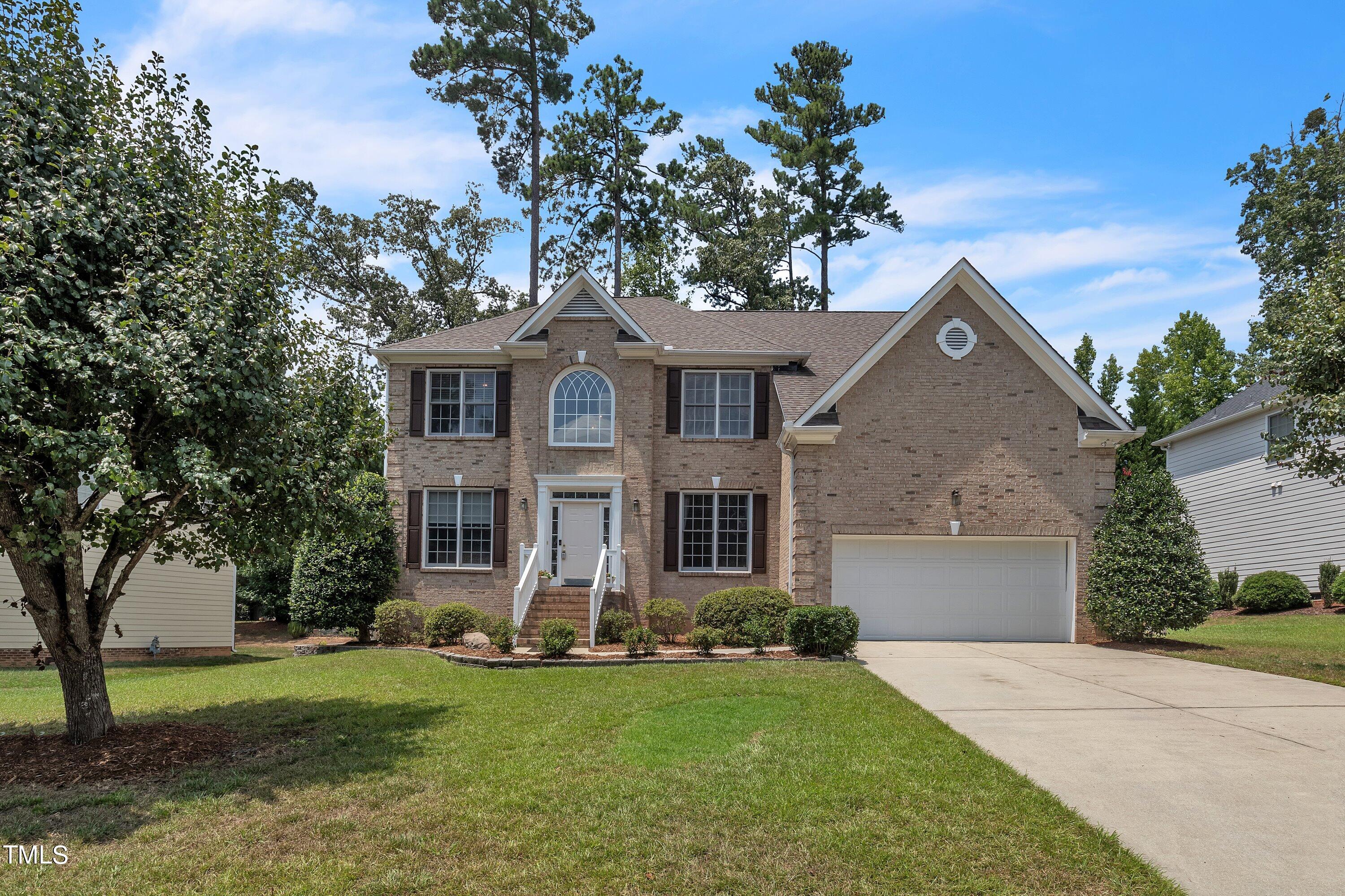a front view of a house with a garden and trees
