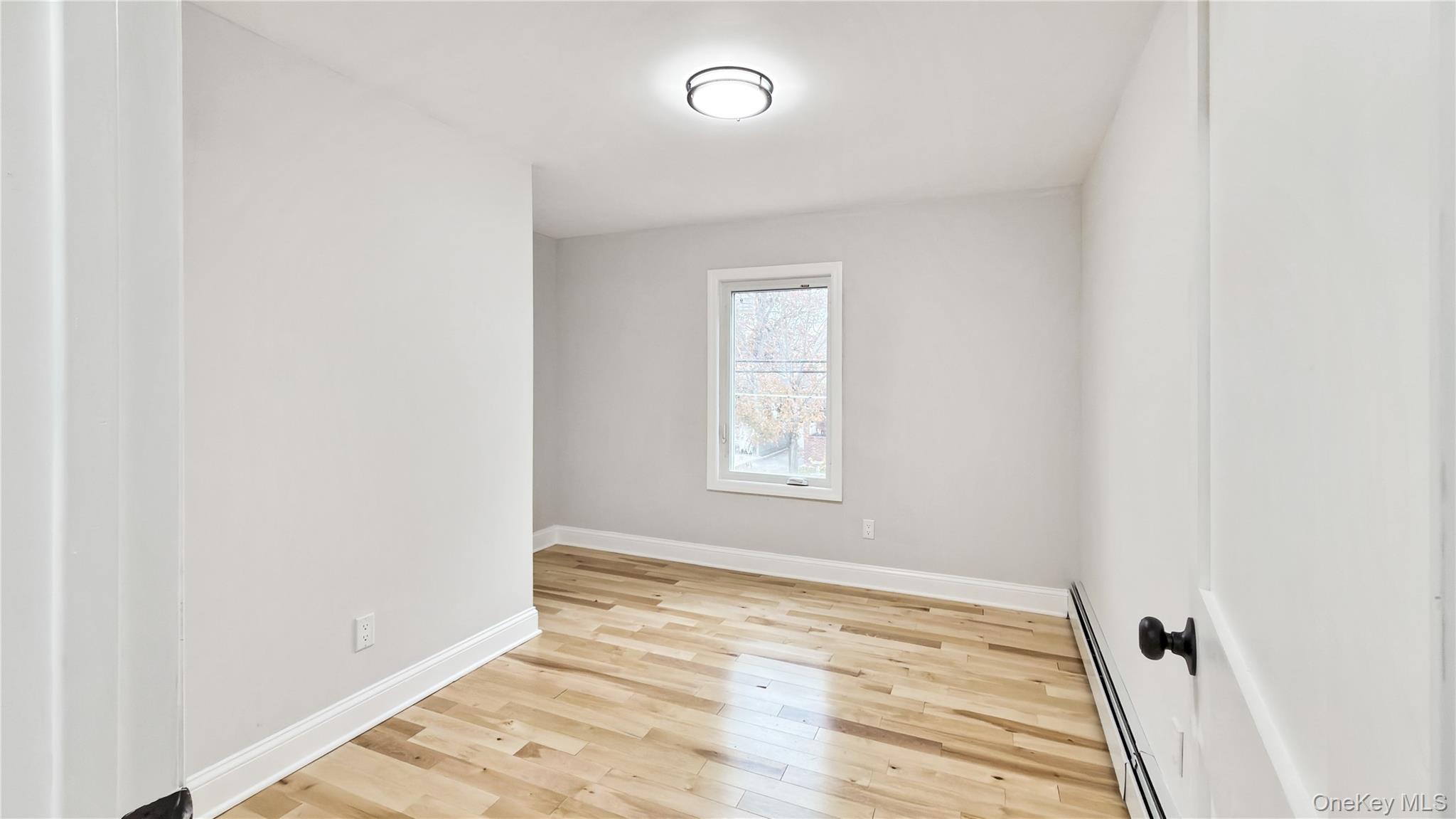 64 South Montgomery Street Valley Stream, NY 11580 - Photo 27 of 47 Spare room featuring a baseboard radiator and light wood-style floors