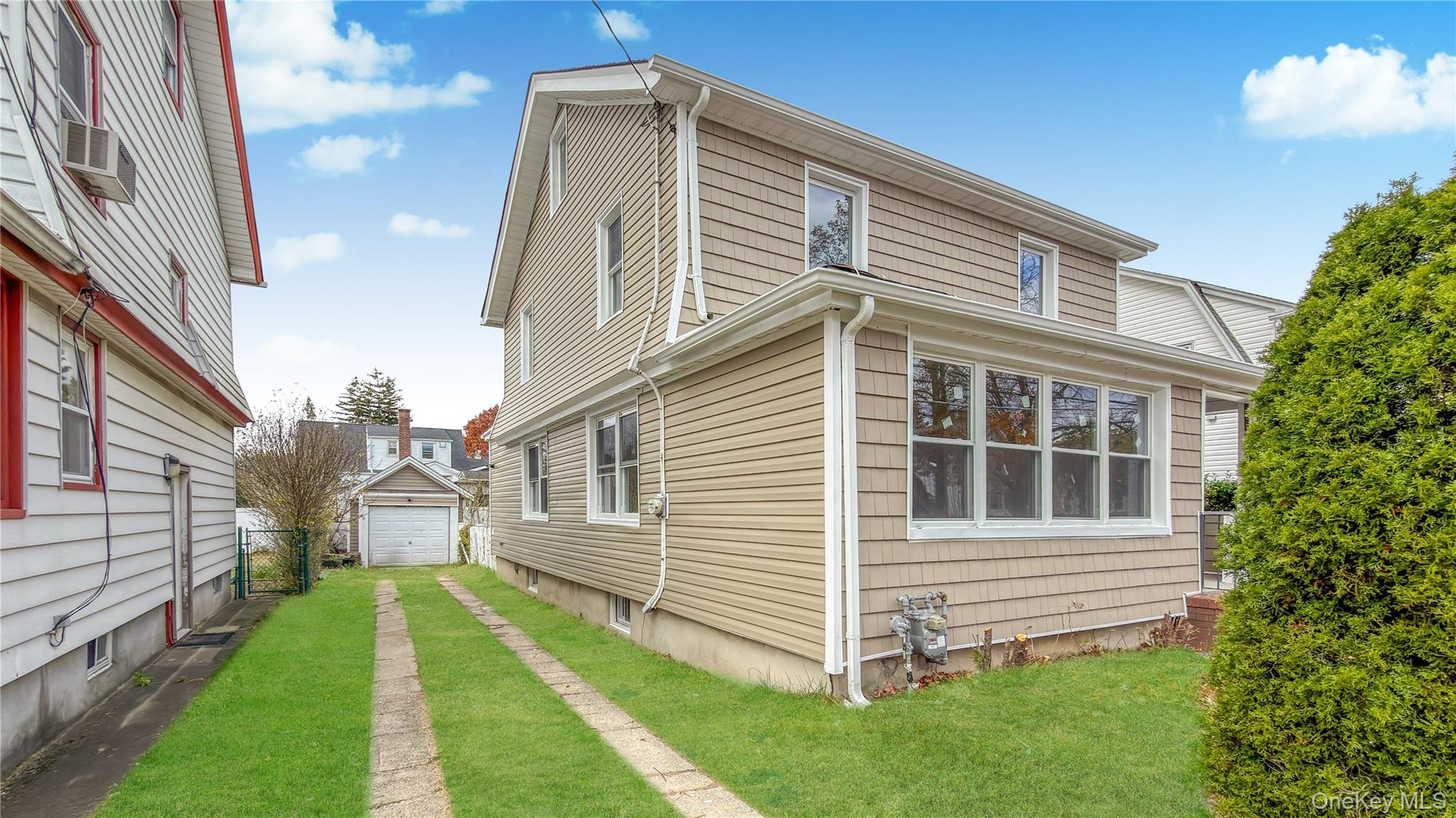 64 South Montgomery Street Valley Stream, NY 11580 - Photo 10 of 47 View of property exterior featuring a detached garage, a yard, and an outdoor structure