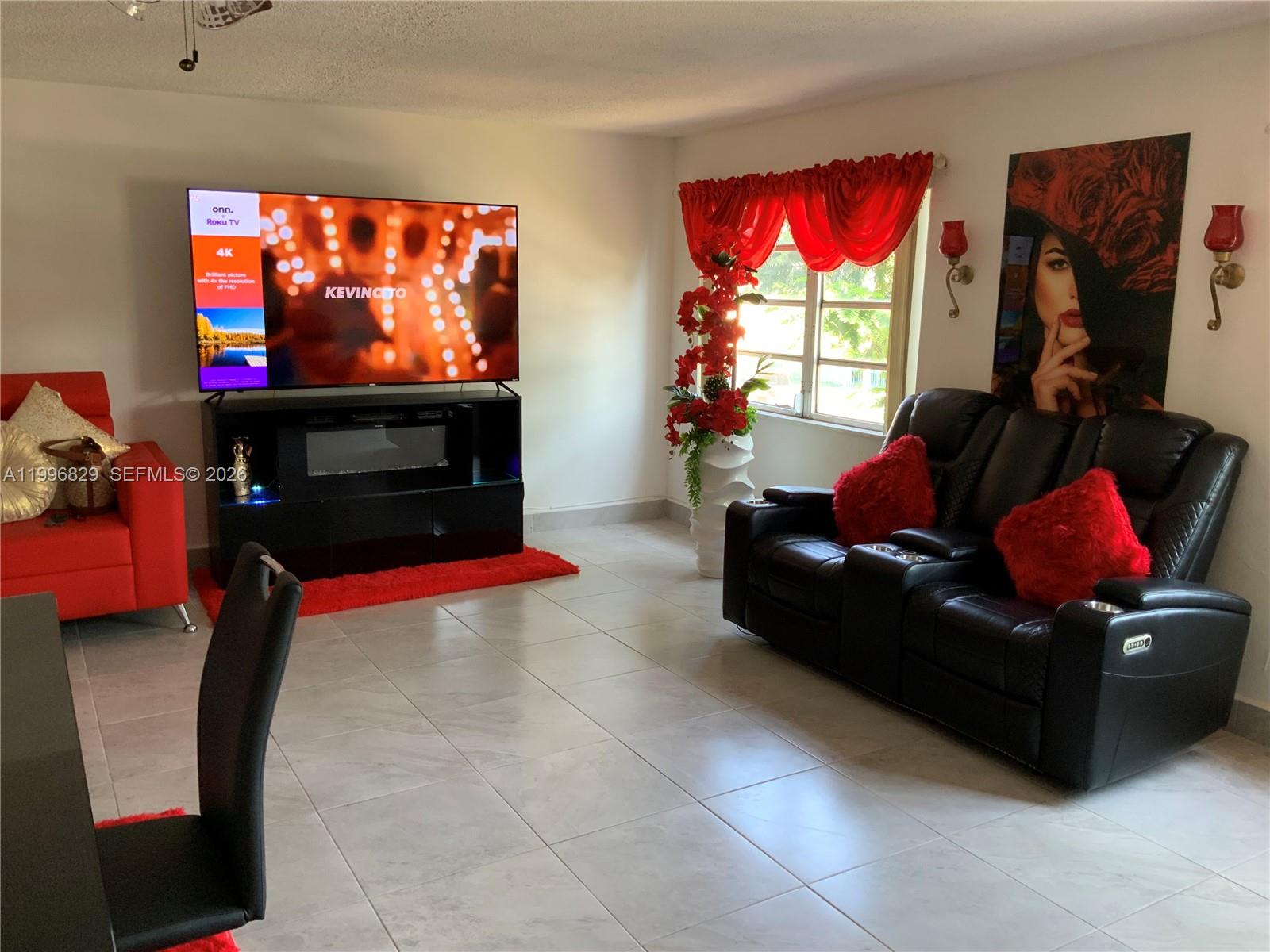 1300 West 53rd Street, Unit 35 Hialeah, FL 33012 - Photo 7 of 9 a living room with furniture a flat screen tv and a fireplace