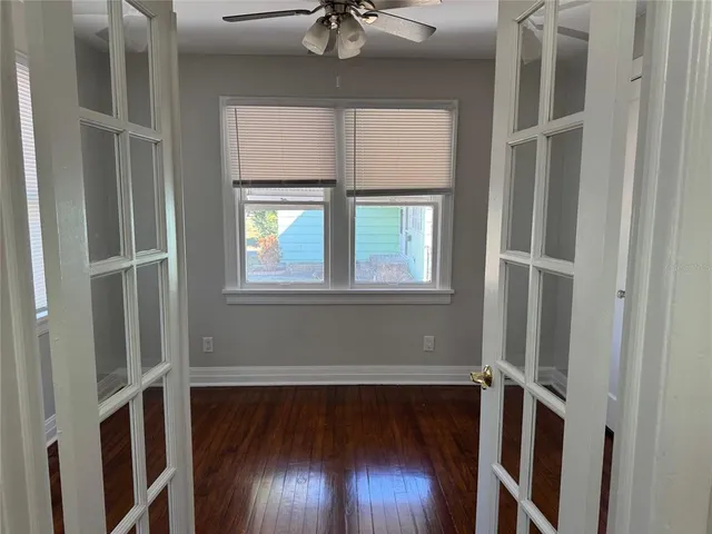 a view of an empty room with wooden floor and a window