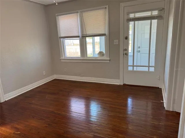 a view of an empty room with wooden floor and a window