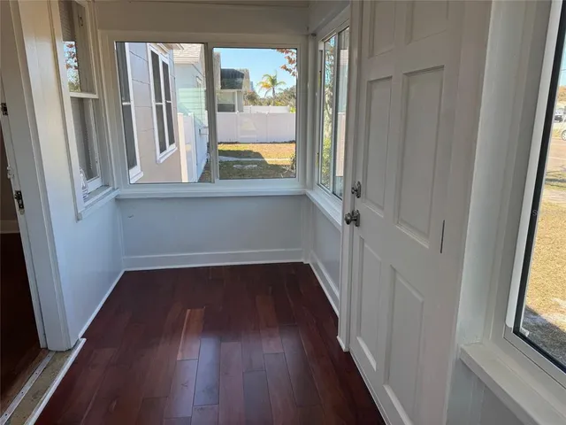 a view of a hallway with wooden floors and a window