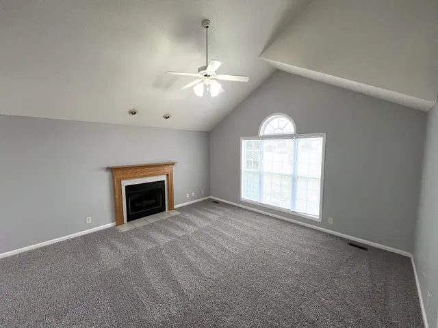 an empty room with chandelier fan and windows
