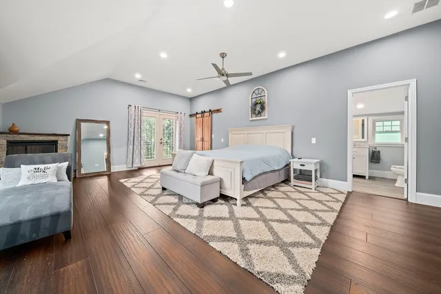 a spacious bedroom with a bed couches and wooden floor