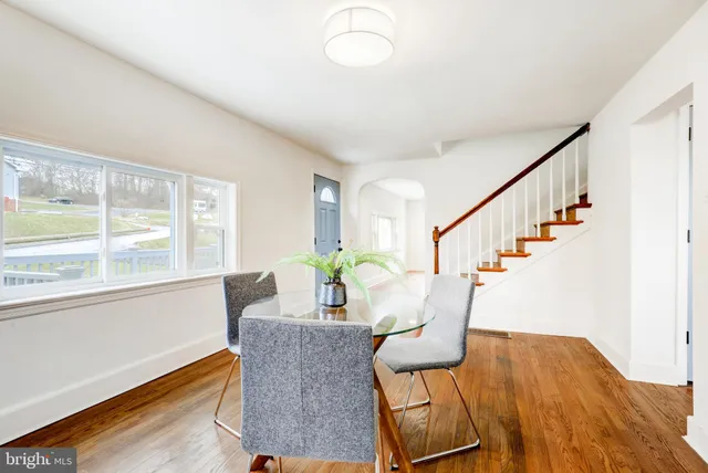 a dining room with furniture a potted plant and wooden floor