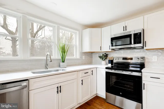 a kitchen with granite countertop a stove a sink and a microwave