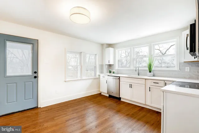 a large white kitchen with cabinets a sink and a window