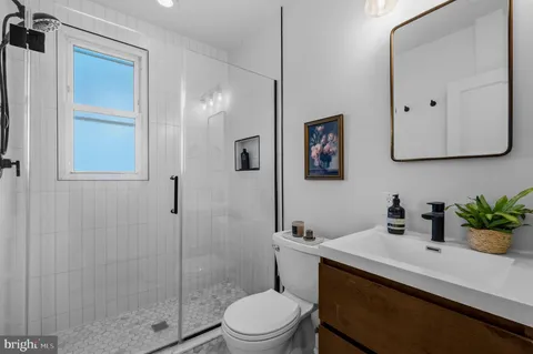 a bathroom with a sink a toilet a shower and a mirror