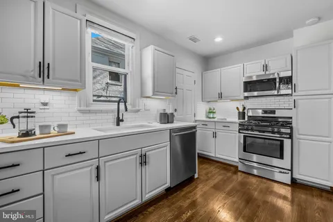 a kitchen with stainless steel appliances granite countertop a sink and cabinets with wooden floors