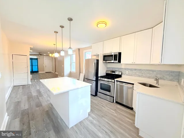 a kitchen with kitchen island a sink dishwasher stove and oven with wooden floor