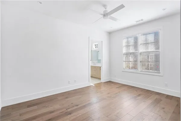 an empty room with wooden floor and fan