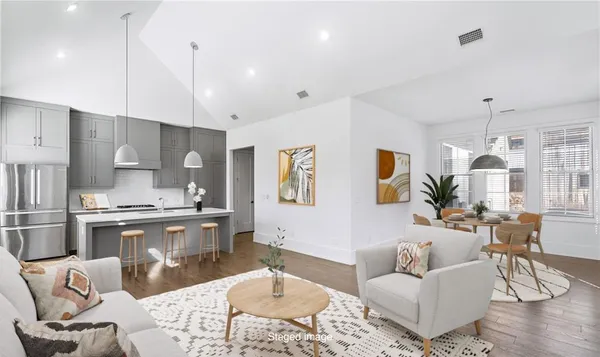 a living room with stainless steel appliances kitchen island granite countertop furniture and a wooden floor