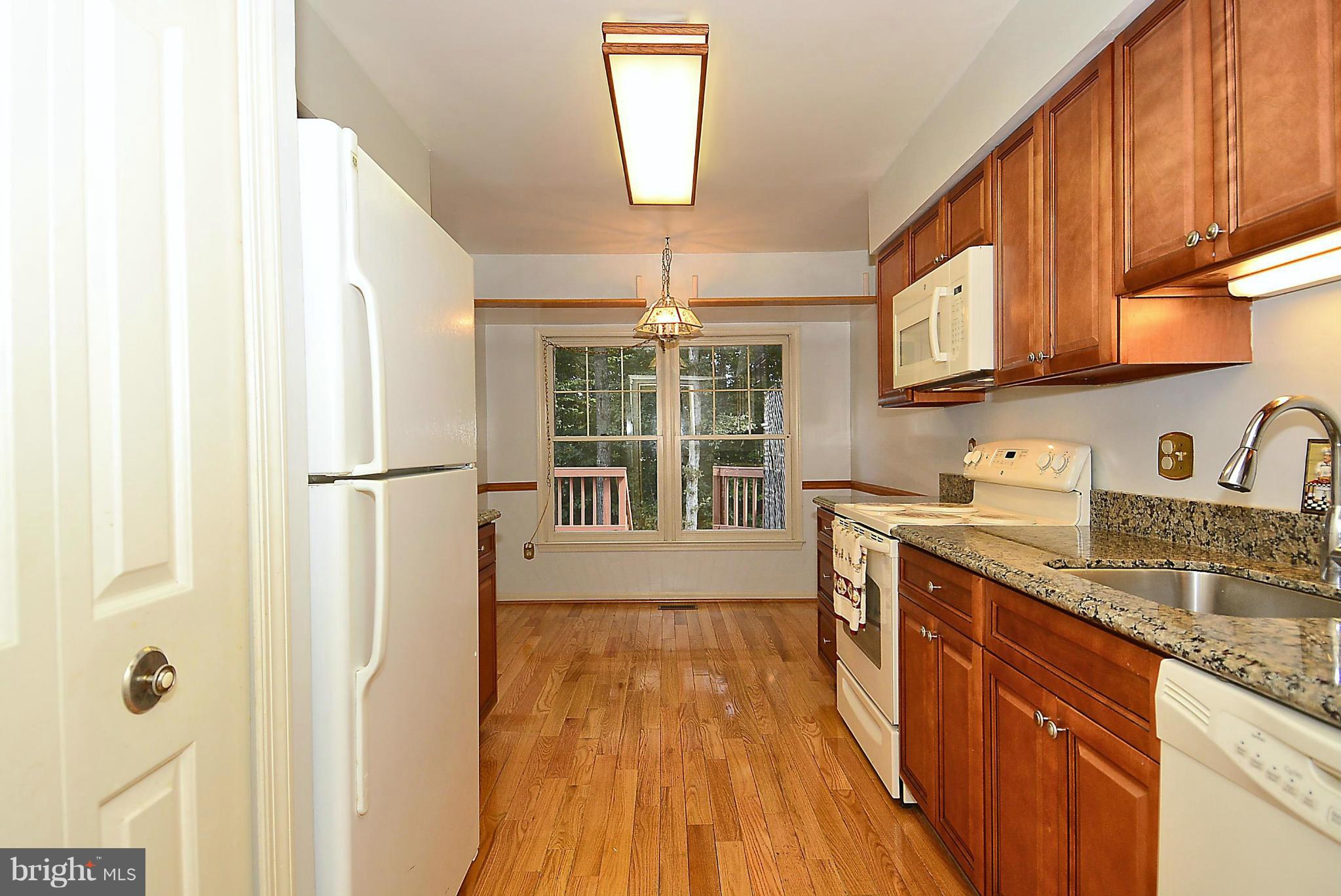 6277 Rathlin Drive Springfield, VA 22152 - Photo 4 of 30 a kitchen with kitchen island granite countertop a sink appliances cabinets and a large window