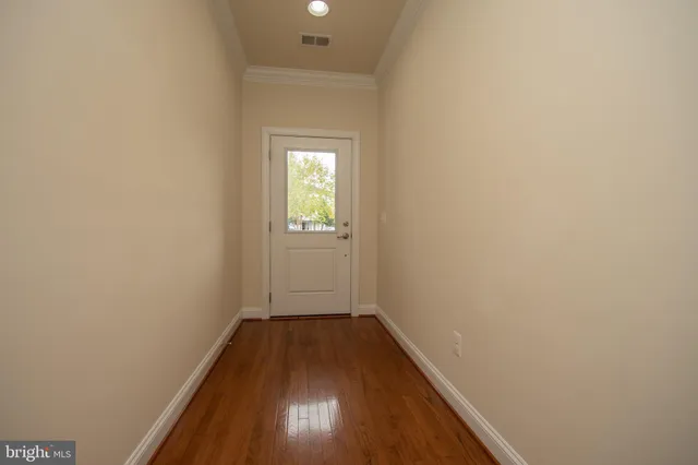 a view of a hallway with wooden floor and a window