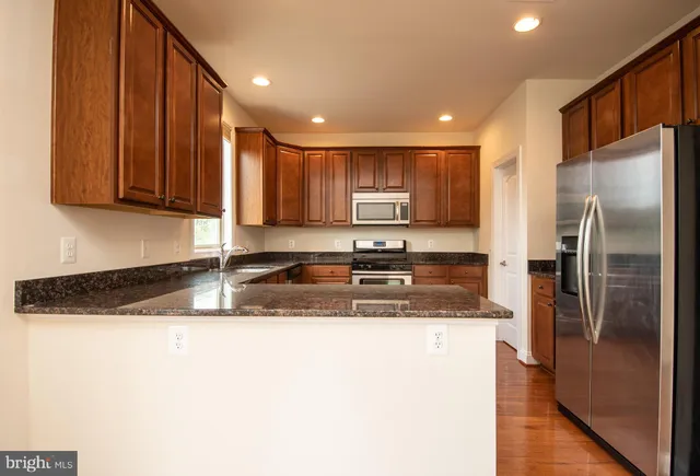 a kitchen with stainless steel appliances granite countertop wooden cabinets a stove and a sink